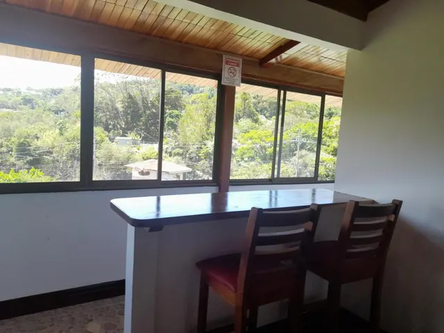 Barra con sillas altas frente a un ventanal con vista al bosque