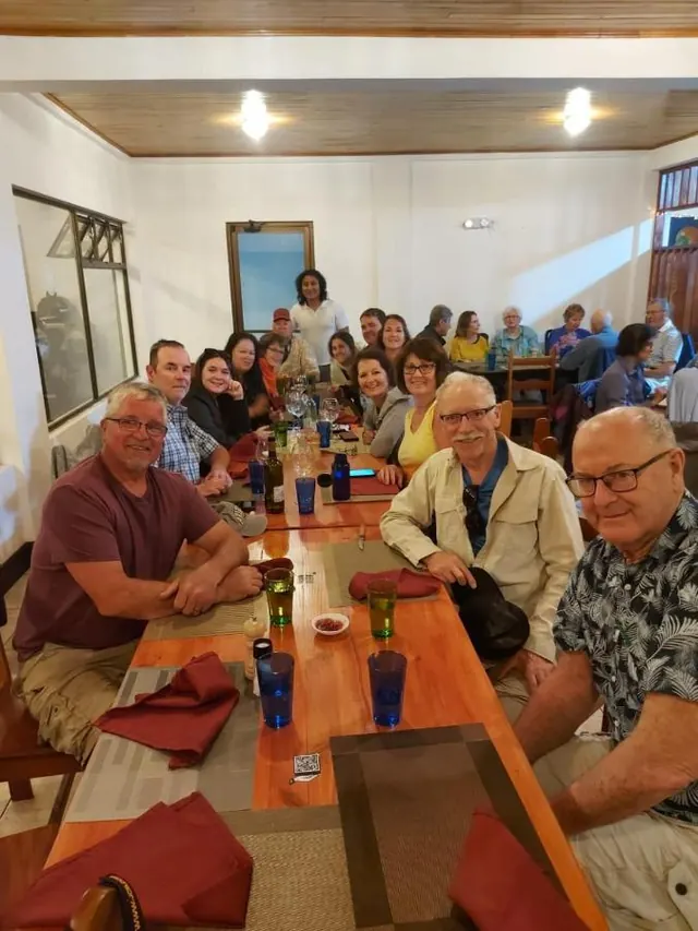 Un grupo grande de huéspedes cenando juntos en una mesa larga del restaurante