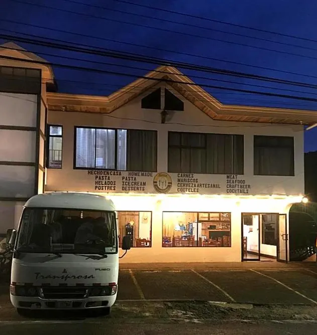 Fachada del hotel de noche, con las ventanas del restaurante encendidas