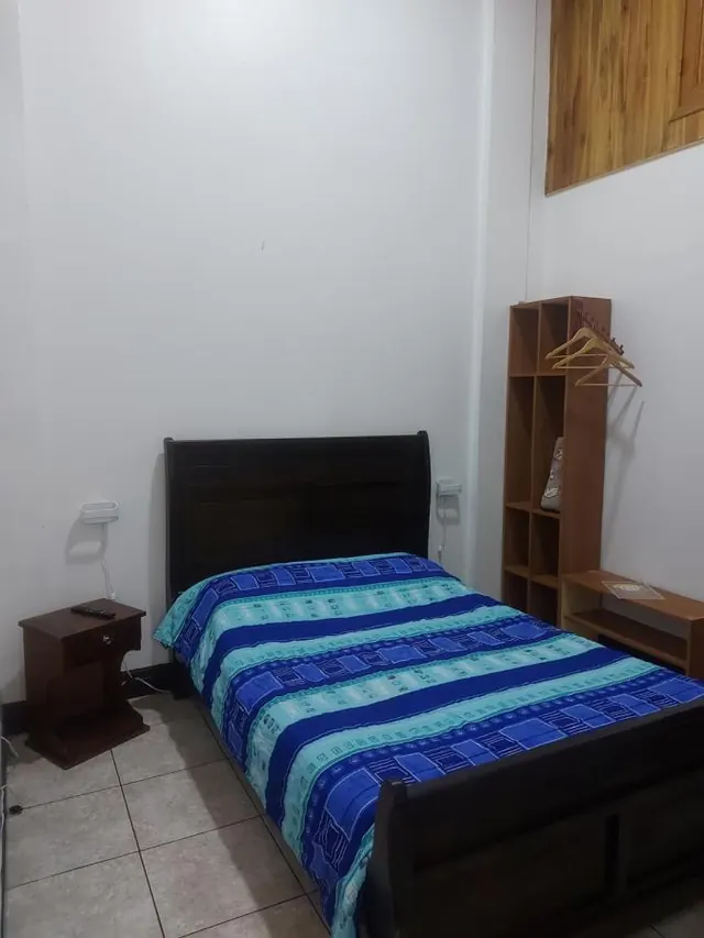 Habitación con cama y cobija de rayas azules y estante de madera